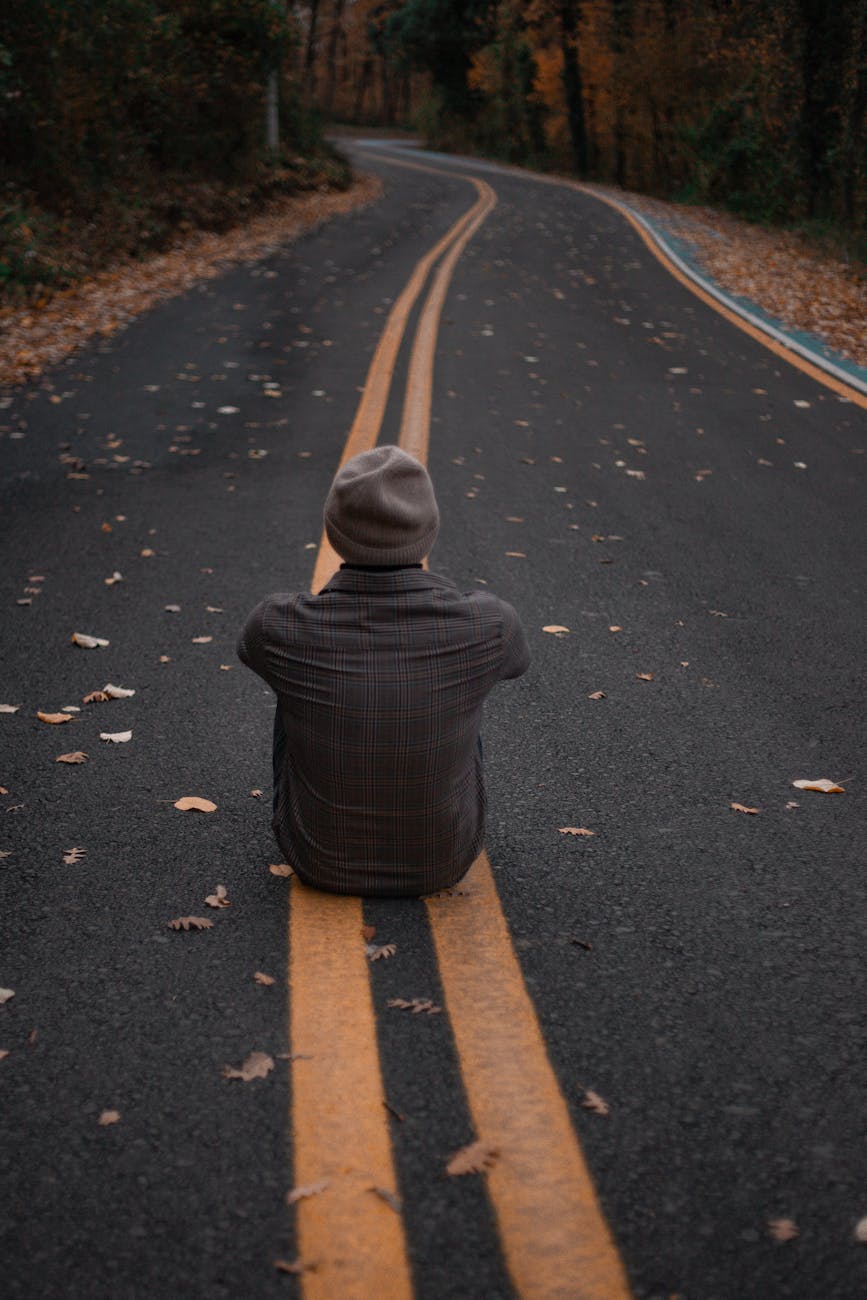 contemplative man sitting on autumn road